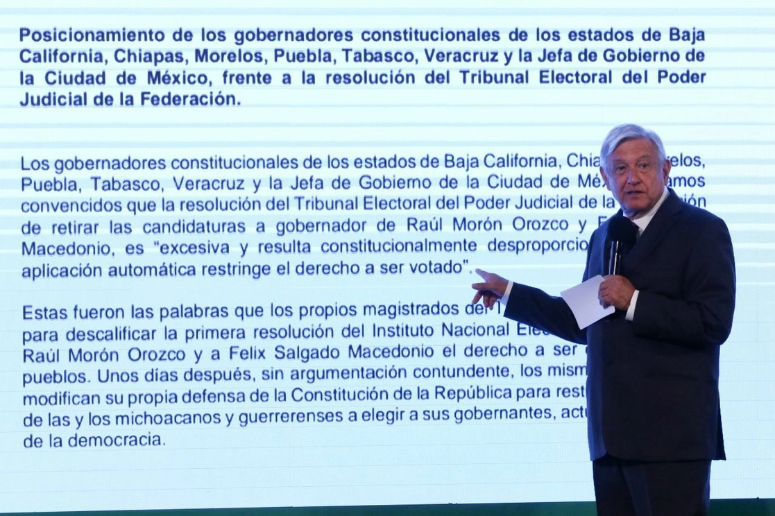 El presidente López Obrador muestra el manifiesto de mandatarios de Morena en respuesta al fallo del INE y ratificado por el TEPJF sobre el retiro de dos candidaturas a gubernaturas durante su conferencia desde Palacio Nacional, el 30 de abril de 2021. Foto Cuartoscuro 