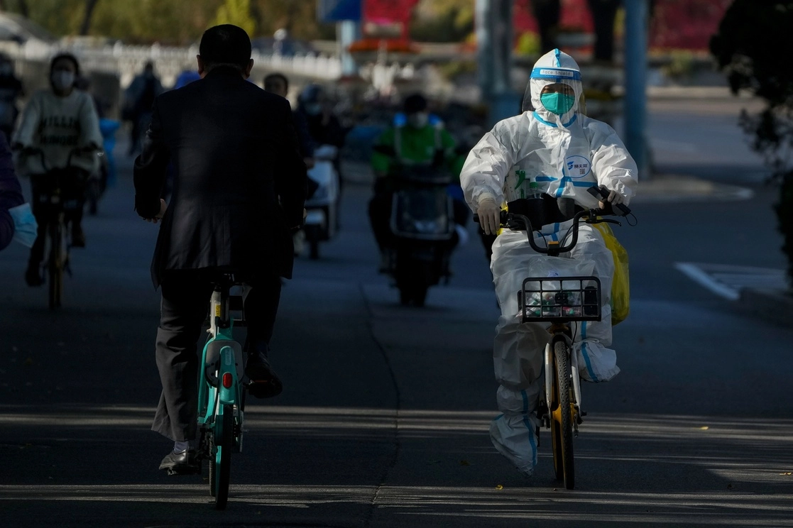 Ante las estrictas medidas en la capital Pekín, un trabajador lleva un traje protector mientras circula por la calle. Foto Ap 



