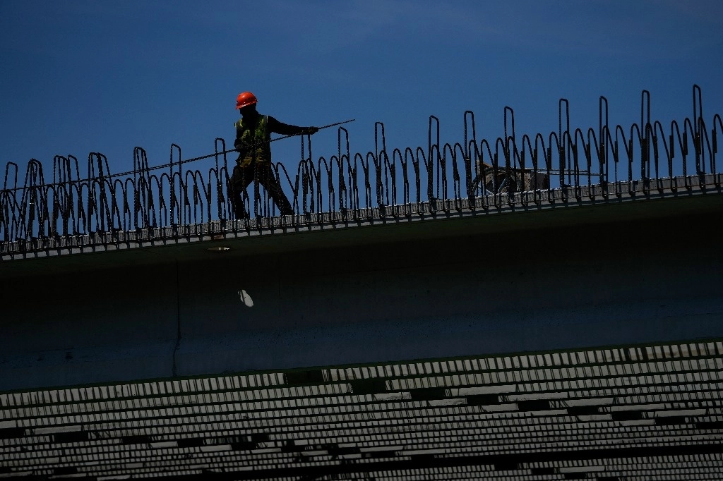 Un trabajador carga un cable de acero en una obra de construcción. Foto Ap
