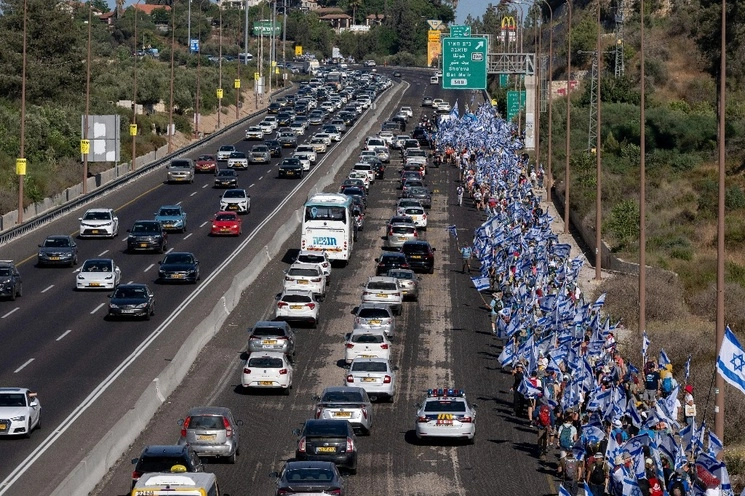 Los israelíes marchan a lo largo de la autopista 1 en su camino a Jerusalén cerca de Moshav Shoresh en Israel, como parte de las protestas contra los planes del gobierno del primer ministro Benjamin Netanyahu para reformar el sistema judicial, el viernes 21 de julio de 2023. Foto Ap