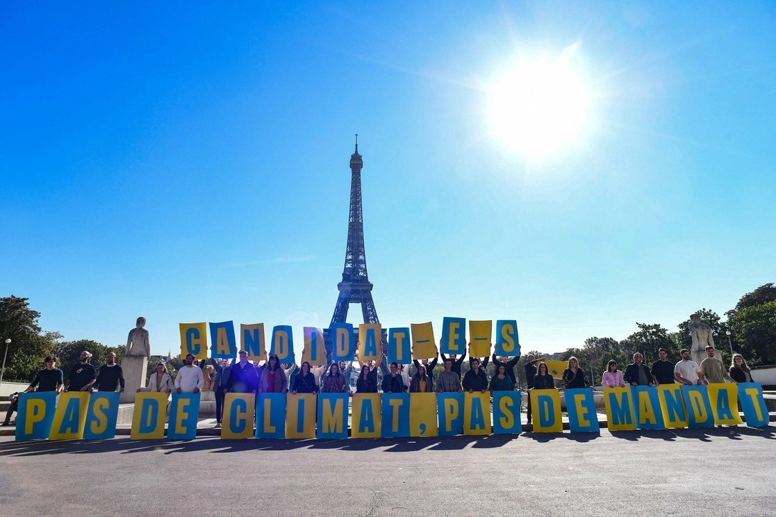 Activistas en contra del cambio climático de cuatro diferentes ONGs sostienen una pancarta que dice 'Candidatos, sin clima, sin mandato' frente a la Torre Eiffel en París, el 14 de octubre de 2021. Foto Afp 
