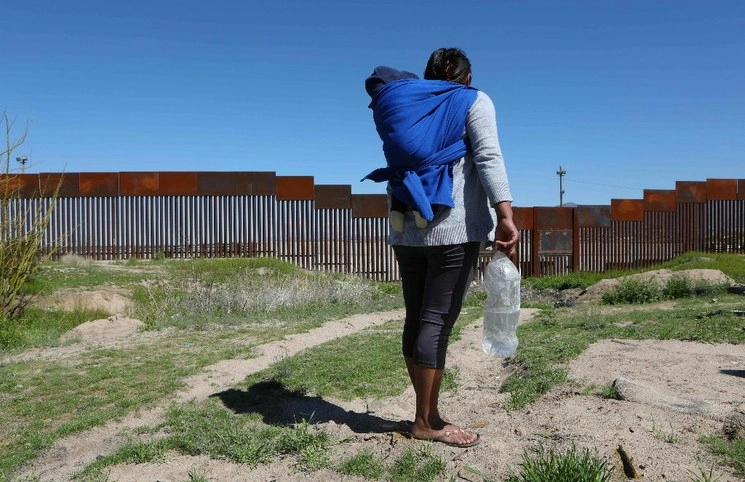 Una migrante carga a su niño en la espalda, mientras se encuentra parada frente al muro fronterizo que divide Sunland Park, Nuevo México, con Ciudad Juárez Chihuahua. Foto Herika Martínez / Afp