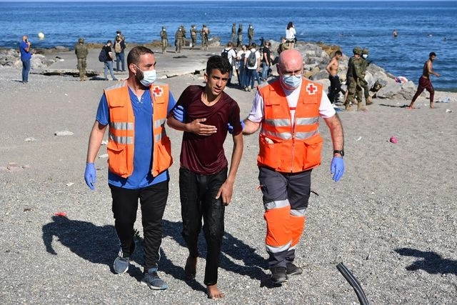 Miembros de la Cruz Roja asisten a un migrante que llegó nadando al enclave español de Ceuta. Foto Afp
