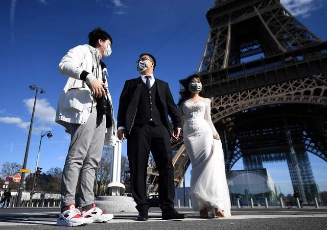 Turistas vietnamitas con tapabocas en la Torre Eiffel, para tomas fotografías por su matrimonio. Foto Afp