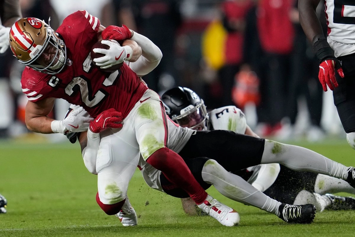 El corredor de los San Francisco 49ers, Christian McCaffrey (23), es tackleado por el esquinero de los Atlanta Falcons, Cobee Bryant (37). Foto