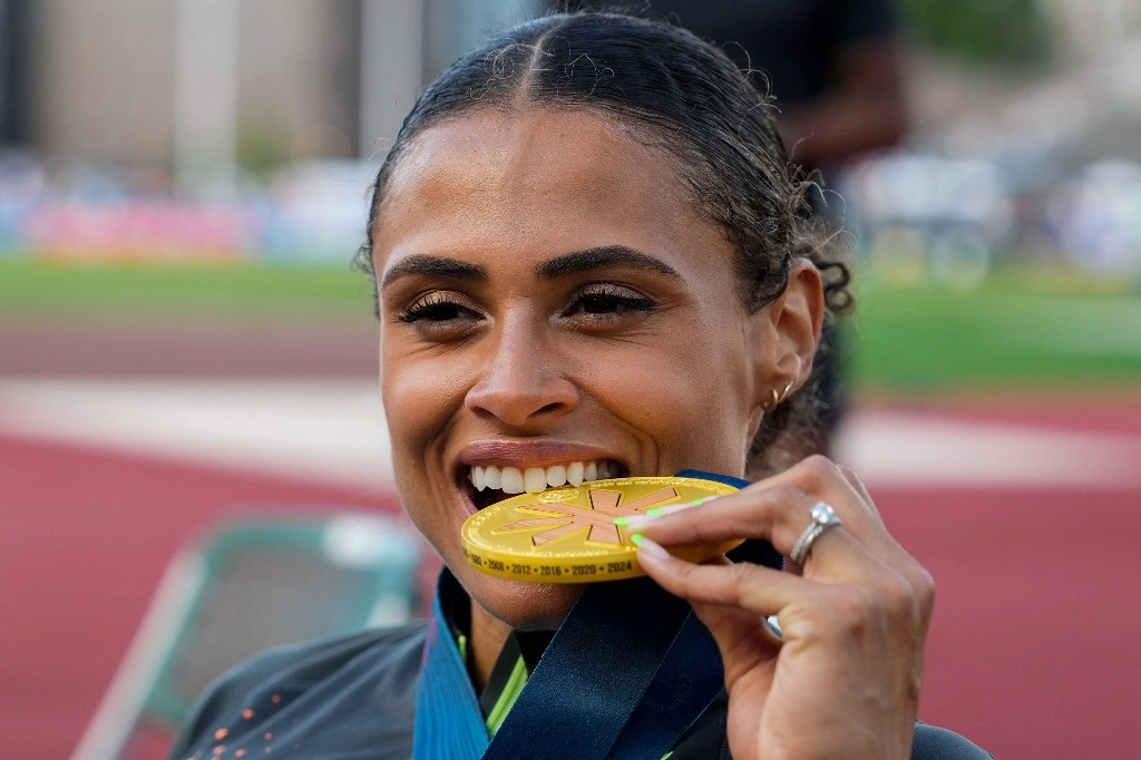 La atleta Sydney McLaughlin-Levrone muerde su medalla de oro después de ganar la carrera femenil con obstáculos en el Hayward Field de Estados Unidos. Foto Ap 