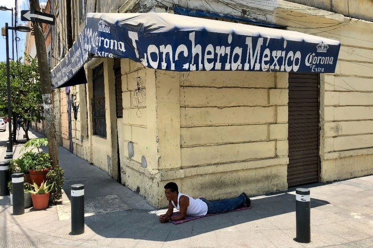En el Barrio de Santa María la Redonda, Colonia Guerrero, en tiempos de Covid-19, José se recuesta en el piso a tomar el fresco, afuera de una lonchería que permanece cerrada por la contingencia sanitaria. Foto Luis Castillo 
