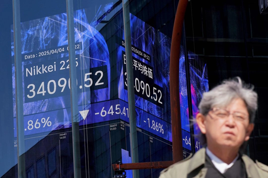 Un hombre pasa junto a un tablero electrónico que muestra los números del Nikkei Stock Average en la Bolsa de Tokio 