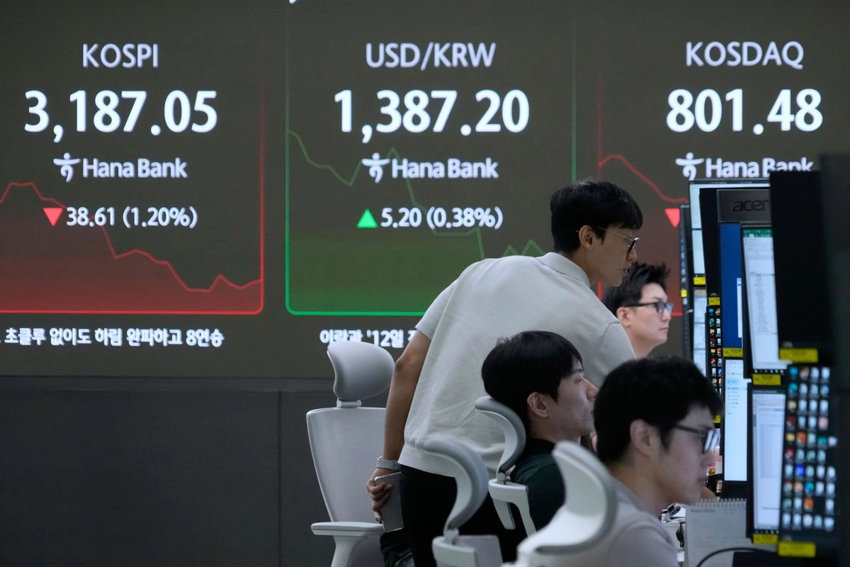 Operadores de divisas observan monitores cerca de una pantalla que muestra el Índice Compuesto de Precios de Acciones de Corea (KOSPI), a la izquierda, y el tipo de cambio entre el dólar estadunidense y el won surcoreano, al centro, en la sala de operaciones de cambio de divisas de la sede del Banco Hana en Seúl, Corea del Sur. Foto 