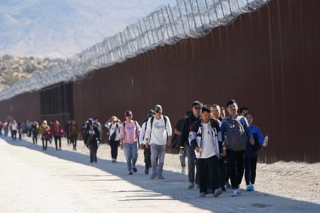 Migrantes indocumentados caminan a un lado del muro fronterizo entre México y Estados Unidos, en octubre de 2023. Foto Ap.