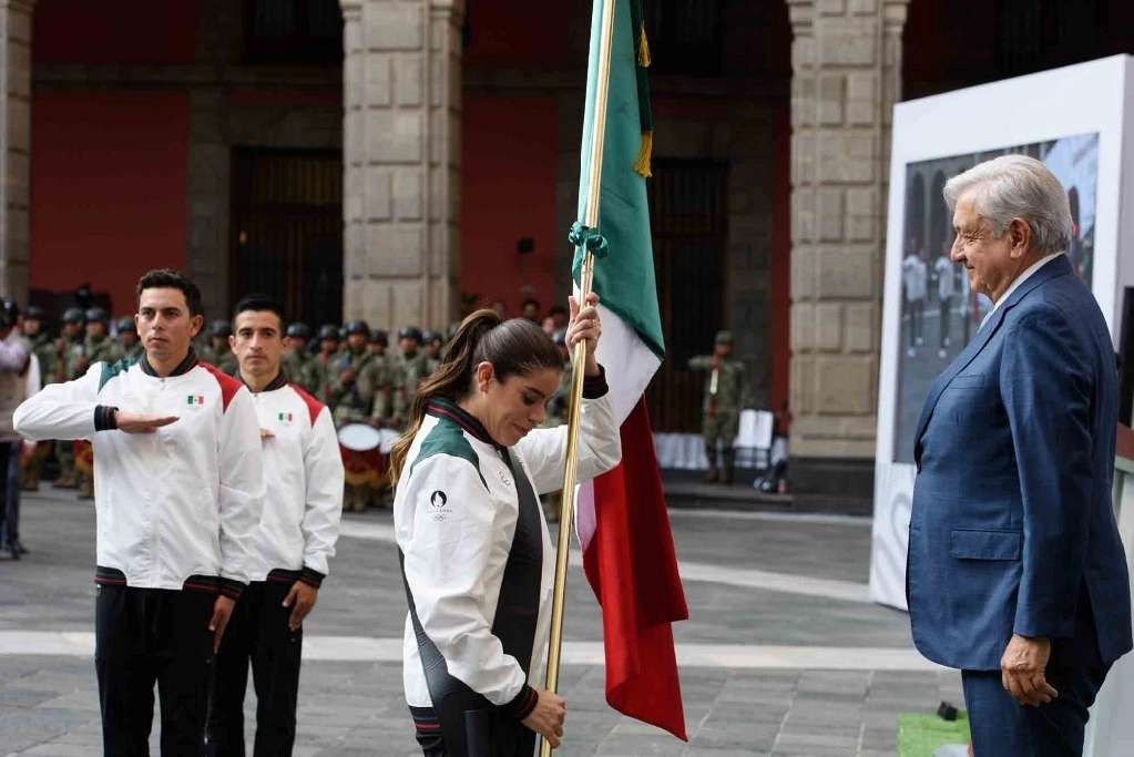 La clavadista Alejandra Orozco fue la encargada de recibir el lábaro patrio de manos del presidente Andrés Manuel López Obrador en Palacio Nacional. Foto Presidencia 