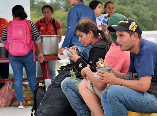 Venezolanos toman un refrigerio mientras esperan el permiso de ingreso a Perú por la frontera con Ecuador. Foto Afp / Archivo