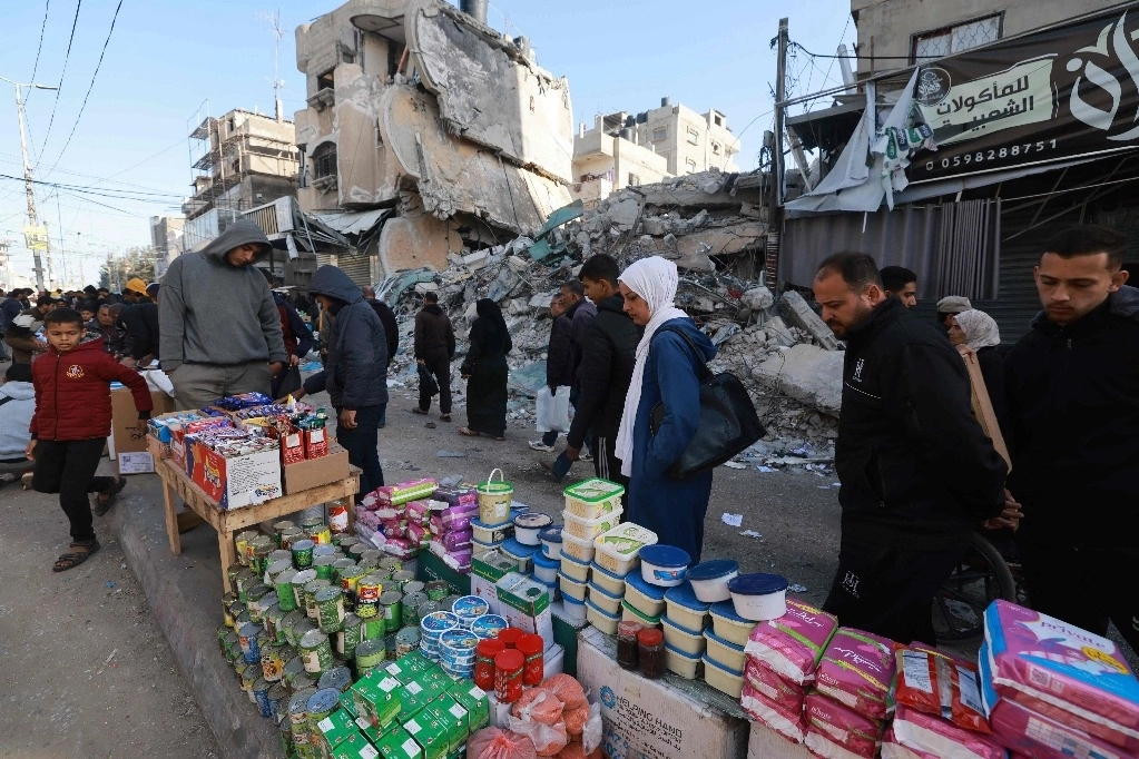 Palestinos pasan el domingo frente a puestos de víveres en una calle de Rafah, en el sur de la franja de Gaza. Los musulmanes se están preparando para las celebraciones del Ramadán en medio de batallas entre el ejército de Israel y el grupo Hamas. Foto Afp 