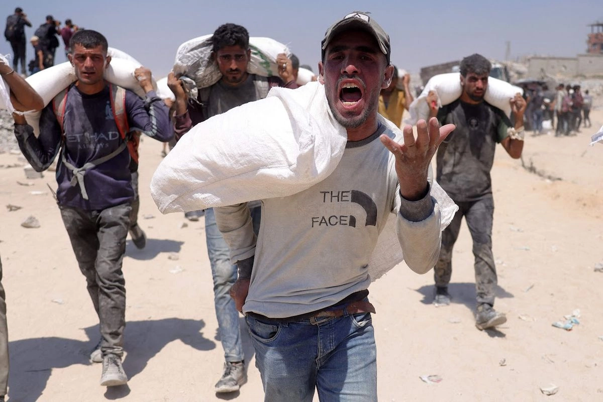 Un grupo de palestinos carga costales de harina luego de que ayer se permitió la entrada de algunos camiones con víveres al norte de Gaza, a través del cruce fronterizo de Zikim