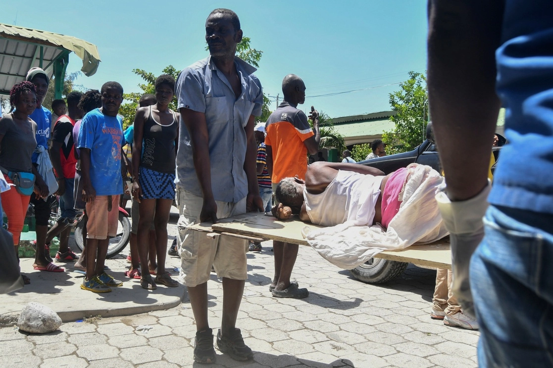 Un hombre ayuda a llevar a una persona rescatada de los escombros en Les Cayes, Haití. Foto Ap