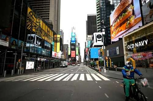 Un repartidor recorre en bicicleta la desierta Times Square en la ciudad de Nueva York. Las celebraciones de Pascua en todo el país comenzaron con iglesias casi vacías. Foto Afp