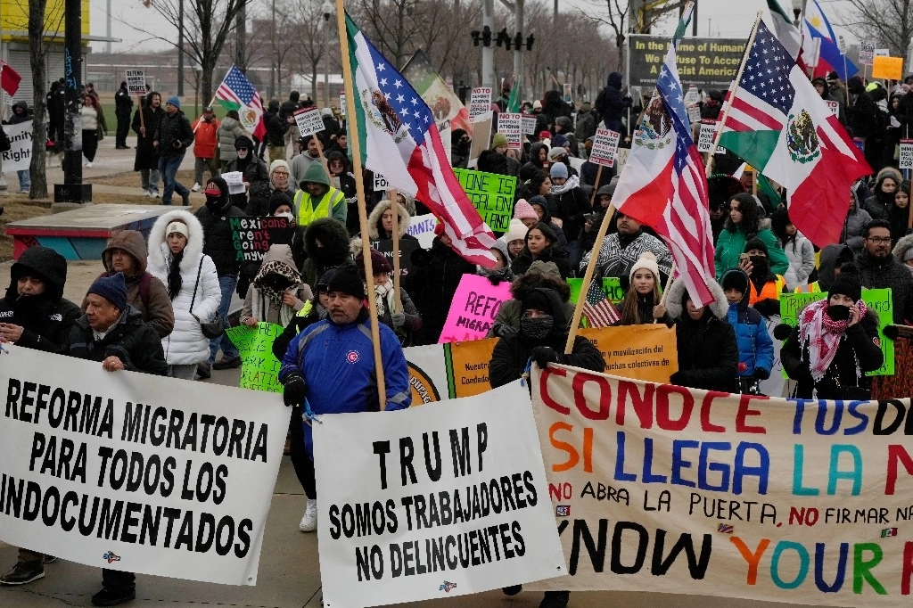 Cientos de personas sostienen carteles y marchan durante la protesta para detener los ataques a los inmigrantes en Chicago. Foto Ap
