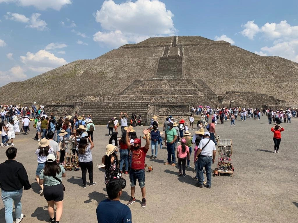 Los visitantes levantaron las manos para "llenarse de energía" al pie de las Pirámides del Sol y de la Luna, en la Zona Arqueológica de Teotihuacán, el 20 de marzo de 2022. Foto Javier Salinas