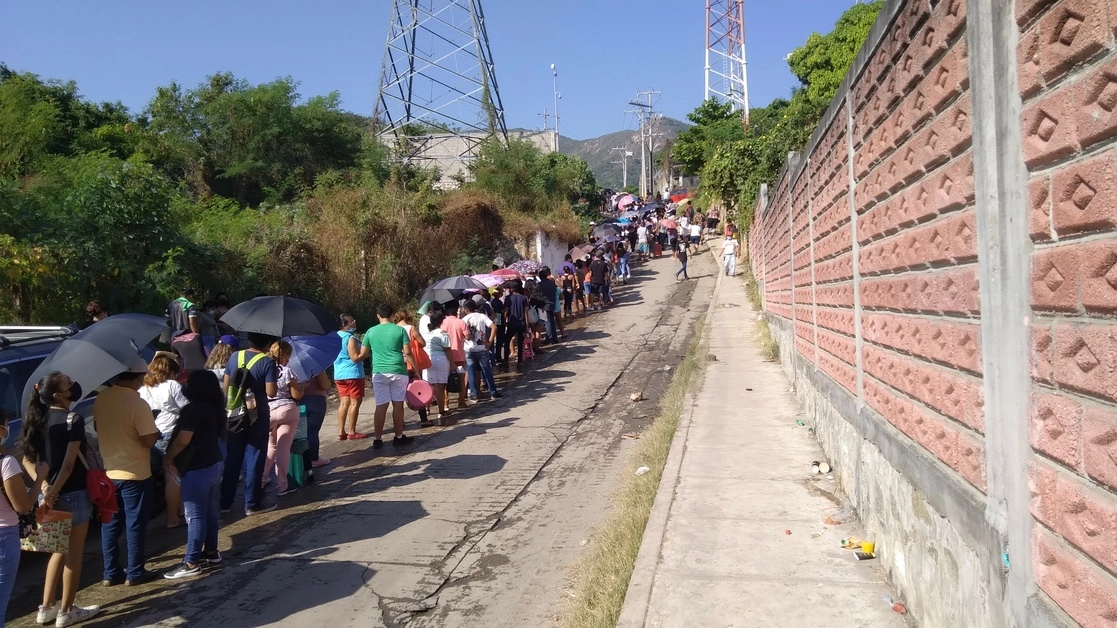 Adolescentes de 15 a 17 años, acompañados de sus padres, realizan una larga fila, bajo una temperatura de 31 grados Celsius, para ingresar al Instituto Tecnológico de Acapulco y recibir la vacuna Pfizer contra el Covid-19, el 9 de diciembre de 2021. Foto Héctor Briseño