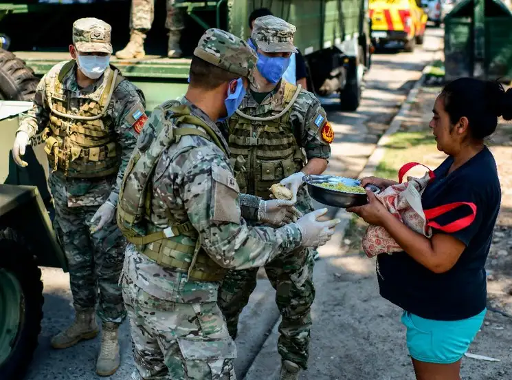 Militares argentinos le entregan comida a una mujer en Quilmes, una zona ubicada a las afueras de Buenos Aires. Foto Afp