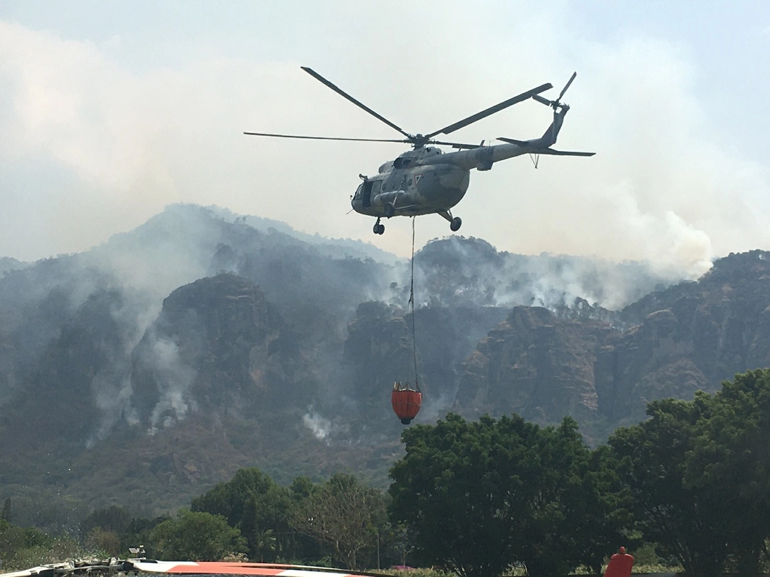 Un helicóptero sobrevuela el centro de mando para el combate al incendio, instalado en la unidad deportiva de Tepoztlán. Foto Rubicela Morelos 