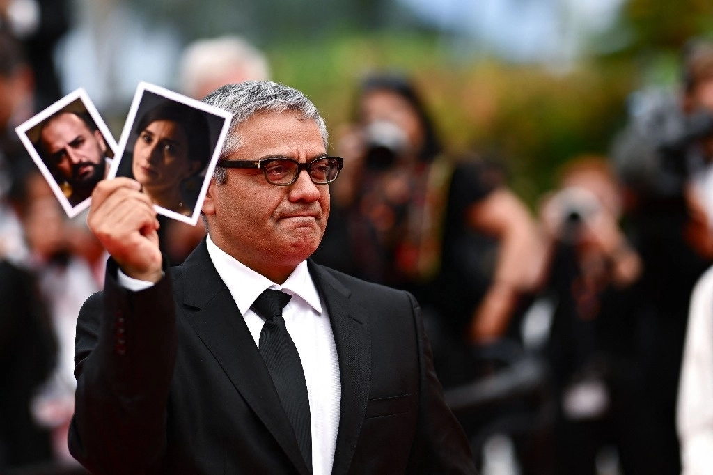 El cineasta iraní Mohammad Rasaulof, muestra las fotos de los actores Missagh Zareh y Soheila Golestan, tras la proyección de su cinta ‘The Seed of the Sacred Fig’ en el festival de Cannes. Foto Afp