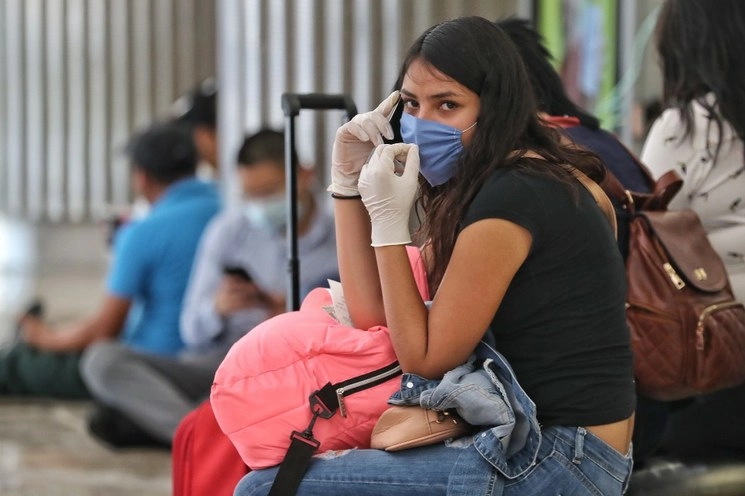 Viajera con cubrebocas y guantes de plástico en el Aeropuerto de la Ciudad de México. Foto LA JORNADA/Marco Peláez