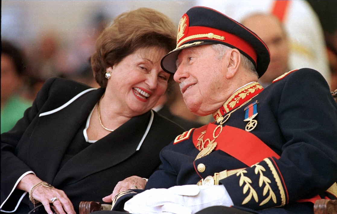Lucía Hiriart despertaba fuertes reacciones por la influencia que tenía en las decisiones del ex dictador chileno Augusto Pinochet y por la fortuna que acumuló su familia. En la imagen, Pinochet escucha a su esposa durante la ceremonia de retiro del mando del ejército en la Academia Militar de Santiago, el 10 de marzo de 1998. Foto Afp 