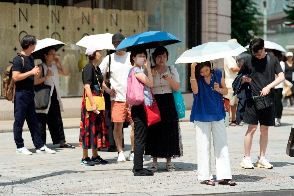 Personas en Tokio se cubren del calor. Foto Ap