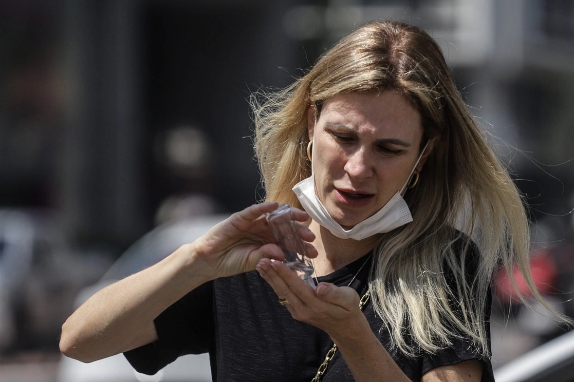 Una mujer utiliza gel antibacterial mientras camina por una calle, en Sao Paulo. Foto Xinhua