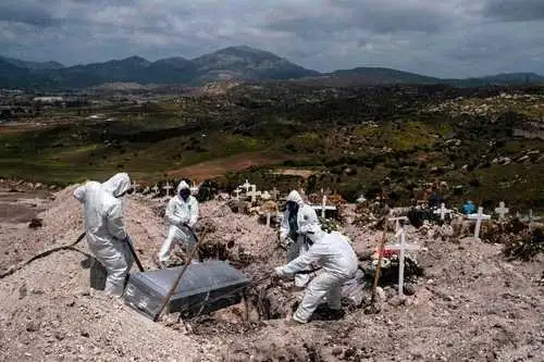 Sepultureros utilizan equipo de protección para enterrar el cuerpo no reclamado de un fallecido por Covid-19 en el cementerio municipal número 13, en Tijuana, Baja California. En el estado se registraron ayer 37 decesos por coronavirus, con los que suman 133. Foto Afp