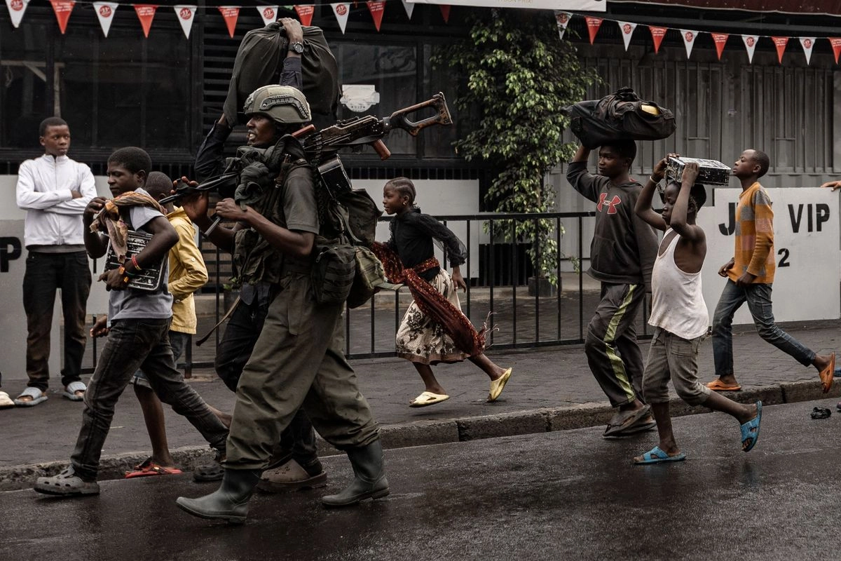 Un miembro del grupo armado M23 camina junto a los residentes por una calle del barrio de Keshero en Goma, el 27 de enero de 2025.