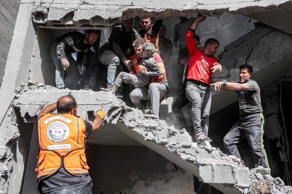 Rescate de un niño tras un bombardeo israelí contra la casa de cuatro pisos de la familia Muqat en el barrio de Zarqa, en el norte de la ciudad de Gaza, el 26 de octubre de 2024. Foto Afp