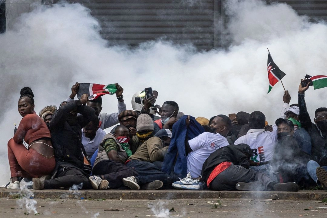 Manifestantes se refugian envueltos en una nube de gas lacrimógeno en el centro de Nairobi, durante una jornada de protestas planificada para conmemorar el primer aniversario de las mortales manifestaciones contra un proyecto fiscal, el 25 de junio de 2025. Foto 