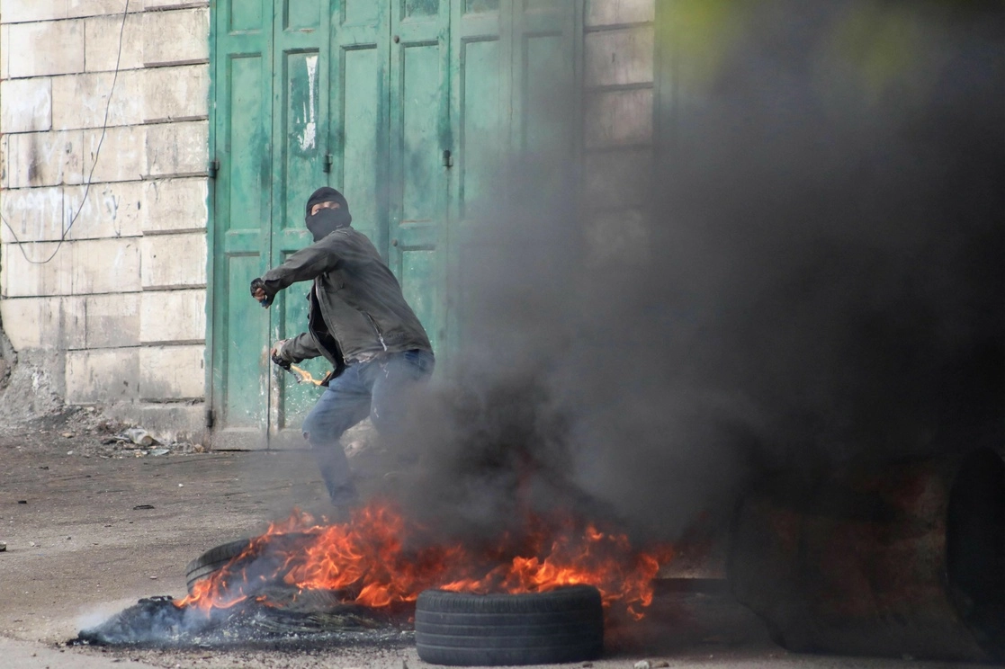 Un manifestante palestino lanza rocas a las fuerzas israelíes en El Hebrón, tras el funeral de uno de los fallecidos en enfrentamientos, el 29 de noviembre de 2022. Foto Afp 