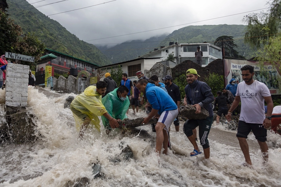Personas colocan rocas para frenar el paso de agua tras las intensas lluvias monzónicas en Bhagsunag, en India, el 12 de julio de 2021. Foto Ap