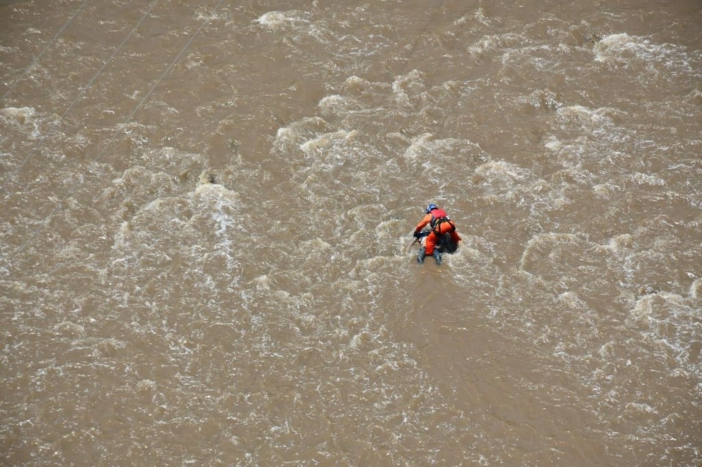 Un elemento de Protección Civil Estatal recoge a una persona fallecida en el río Los Sabinos, Jalisco. Foto La Jornada