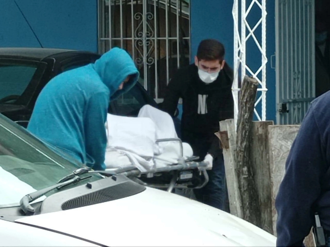 Dos personas trasladan a uno de los fallecidos. Foto Julia Le Duc