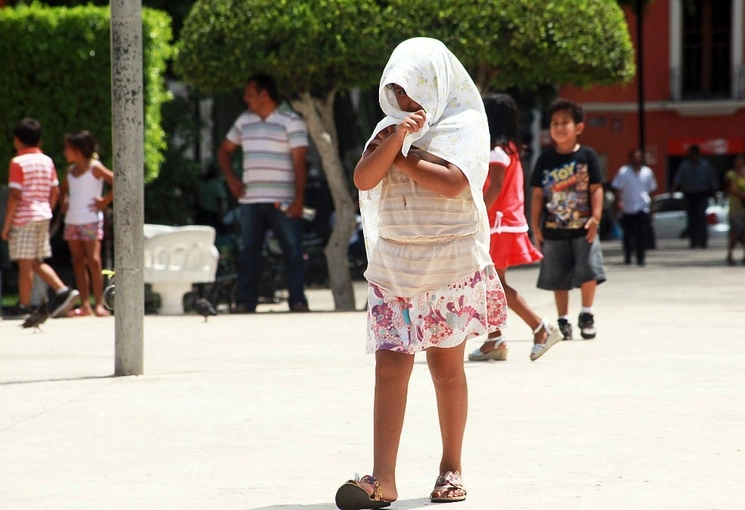 Una niña se cubre con una tela para soportar la radiación solar y las altas temperaturas en La Plaza Grande, en el centro de Mérida, Yucatán, donde ayer se registraron cerca de 40 grados centígrados. Foto Luis A. Boffil 