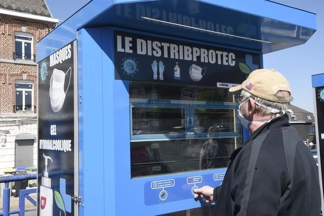 Un hombre utiliza un dispensador automático de cubrebocas, guantes y gel sanitizante en Jeumont, al norte de Francia. Foto Afp 