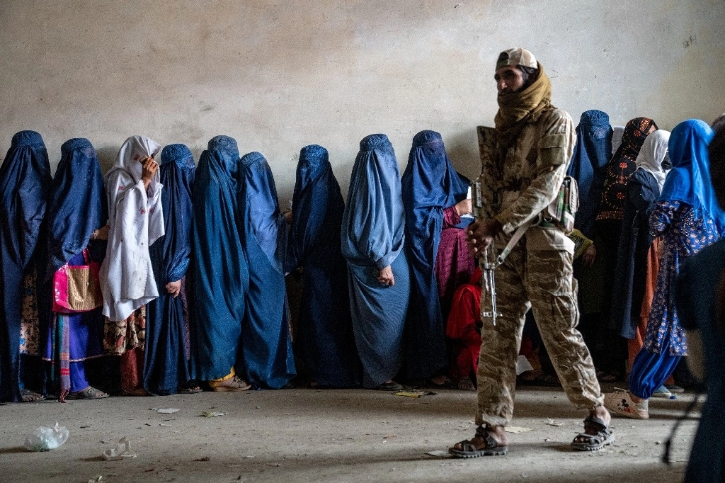 Un combatiente talibán vigila a las mujeres que esperan recibir raciones de alimentos distribuidas por un grupo de ayuda humanitaria, en Kabul, Afganistán.Foto Ap