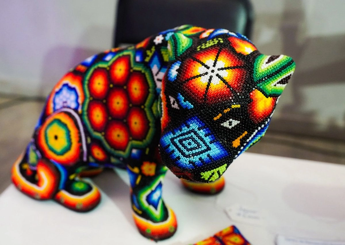 Esta forma de participar, tiene como objetivo promover los trabajos realizados por las personas privadas de la libertad con el fin de estimular su creatividad en la elaboración de productos de arte Wixarika, apoyarlas económicamente y fomentar su integración en la industria del comercio penitenciario. Foto 