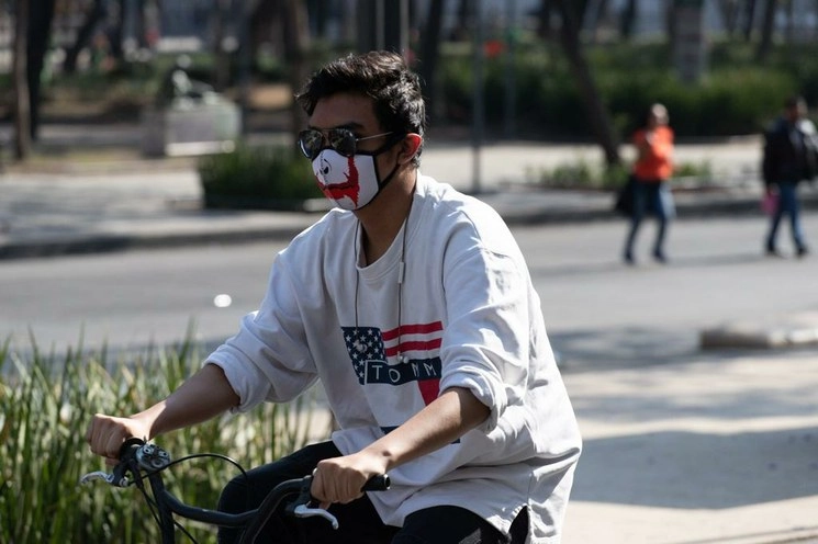 Un joven con cubrebocas monta su bicicleta en la acera de avenida Juárez, en el Centro Histórico. Foto Pablo Ramos