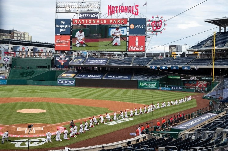 Los Nacionales de Washington y los Yankees de Nueva York se arrodillan mientras sostienen un trozo de tela negra antes del partido inaugural del beisbol de las Grandes Ligas. Foto Ap