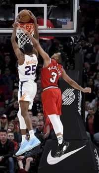 Mikal Bridges, de Phoenix, disputa el balón con CJ McCollum, de Portland. Foto Ap/Archivo