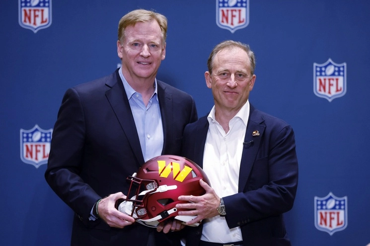 El comisionado de la NFL, Roger Goodell (izq.), presenta al nuevo propietario de los Washington Commanders, Josh Harris, con un casco del equipo, el 20 de julio de 2023. Foto Ap