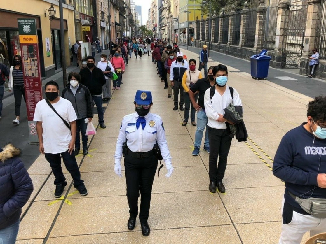 Una policía supervisa que los ciudadanos formen filas para poder ingresar de manera controlada al Zócalo del Centro Histórico. Foto Luis Castillo