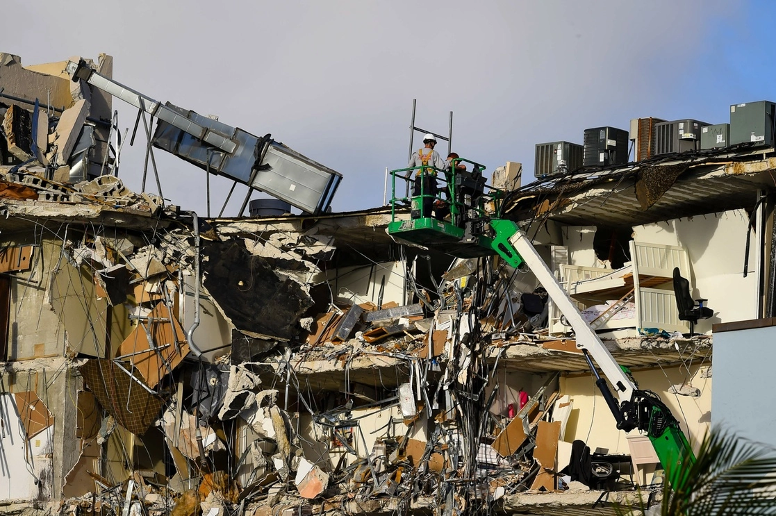 Trabajadores de rescate en una grúa inspeccionan los restos de un edificio parcialmente derrumbado en Surfside al norte de Miami Beach, Florida, el 25 de junio de 2021. Foto Afp