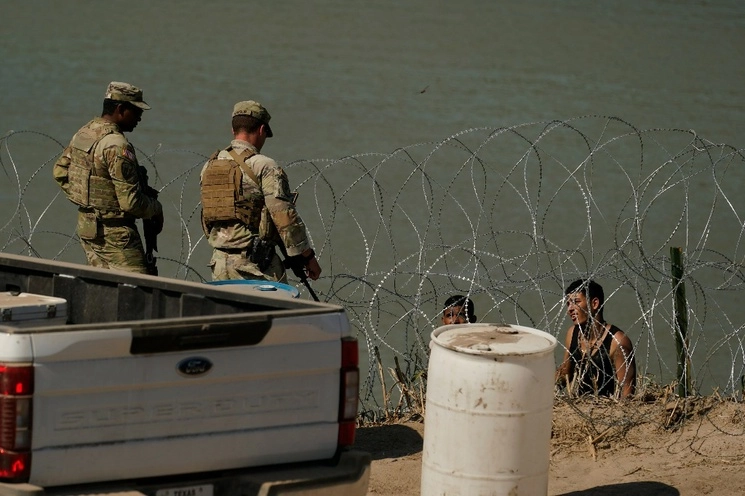 Guardias hablan con migrantes que intentan cruzar el Río Bravo desde México hacia EU. Foto Ap / Archivo 