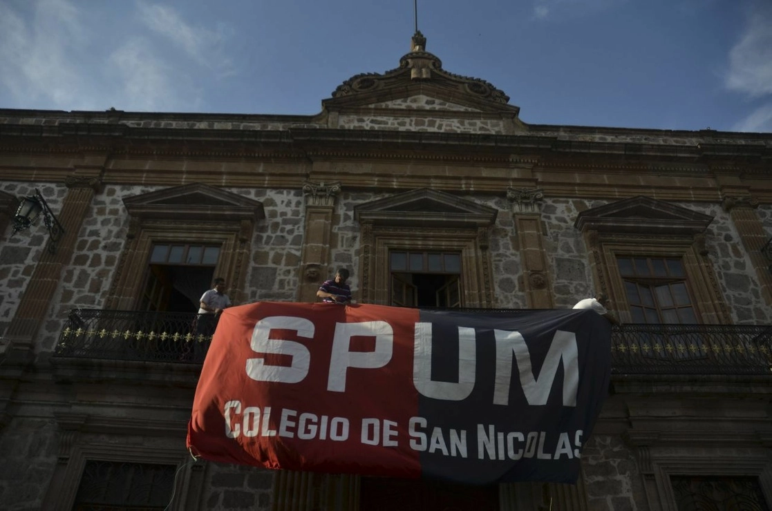 Profesores sindicalizados de la Nicolaíta colocan banderas rojinegras en el antiguo colegio Primitivo y Nacional de San Nicolás de Hidalgo, en el centro de Morelia. Foto Cuartoscuro / Archivo
